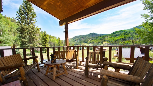 Een houten terras met een tafel en stoelen, met uitzicht op een bebost berggebied.