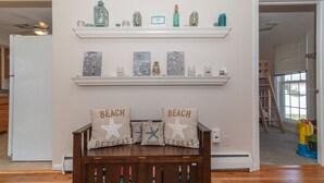 Een woonkamer met een houten bank, decoratieve kussens en een plank met diverse spullen.