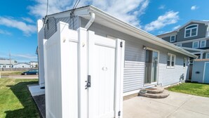 Een gelijkvloers huis met een witte gevel, een voordeur en een klein portaaltje.