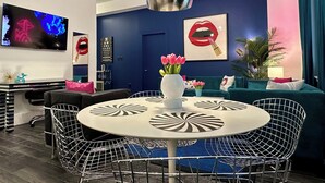 A modern living room with a round table, chairs, a TV, and decorative items.