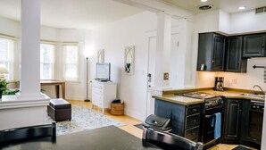 A modern kitchen with dark cabinetry, a built-in oven, and a large island with a sink. - Quaint Downtown Condo (Salt Lake City)