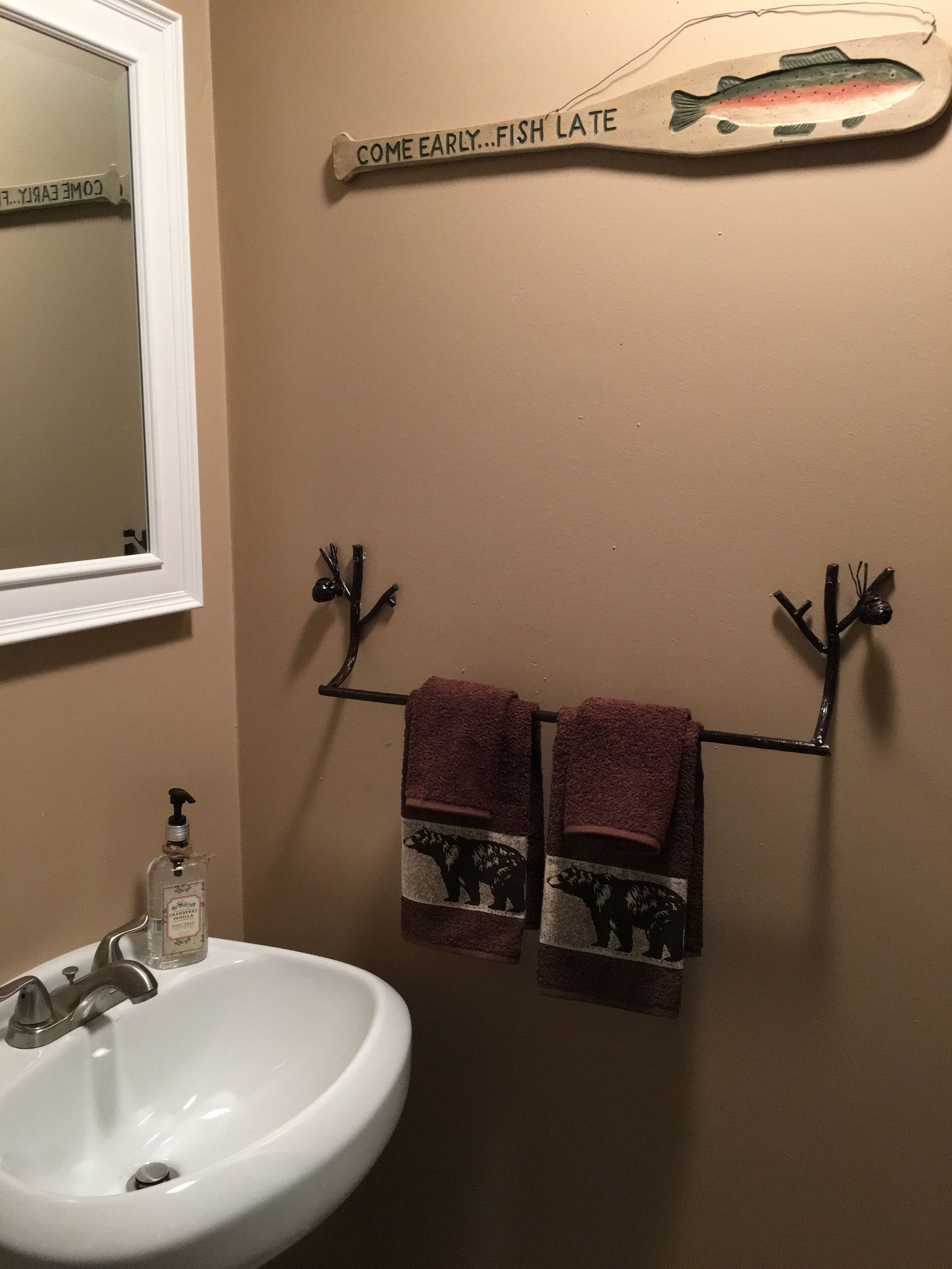 A bathroom with a white sink, a mirror, and a towel rack holding two towels with bear designs.