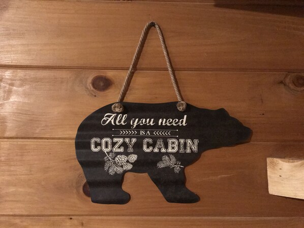 A wooden cabin-shaped sign with text and pinecone decorations. - 3 Bed Cozy Cabin Near Trails, Tippy Dam, Manistee River, Casino. (Wellston)
