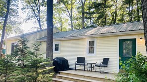 A small cabin with a porch, two chairs, and a table. - 3 Bed Cozy Cabin Near Trails, Tippy Dam, Manistee River, Casino. (Wellston)
