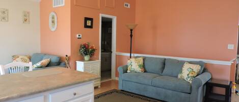 A living room with a blue sofa, a white cabinet, and a beige rug.