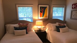 Une chambre d’hôtel avec deux lits, une table de chevet avec une lampe et une œuvre d’art encadrée au mur.