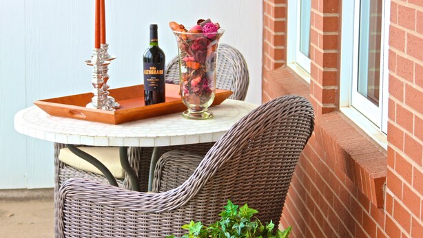 A round table with a bottle of wine, a candle, and a glass vase with dried flowers.