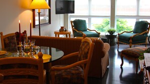 A dining area with a round table, chairs, candles, and a television on the wall.