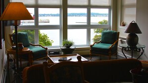 A room with two green armchairs, a wooden table, and a lamp.