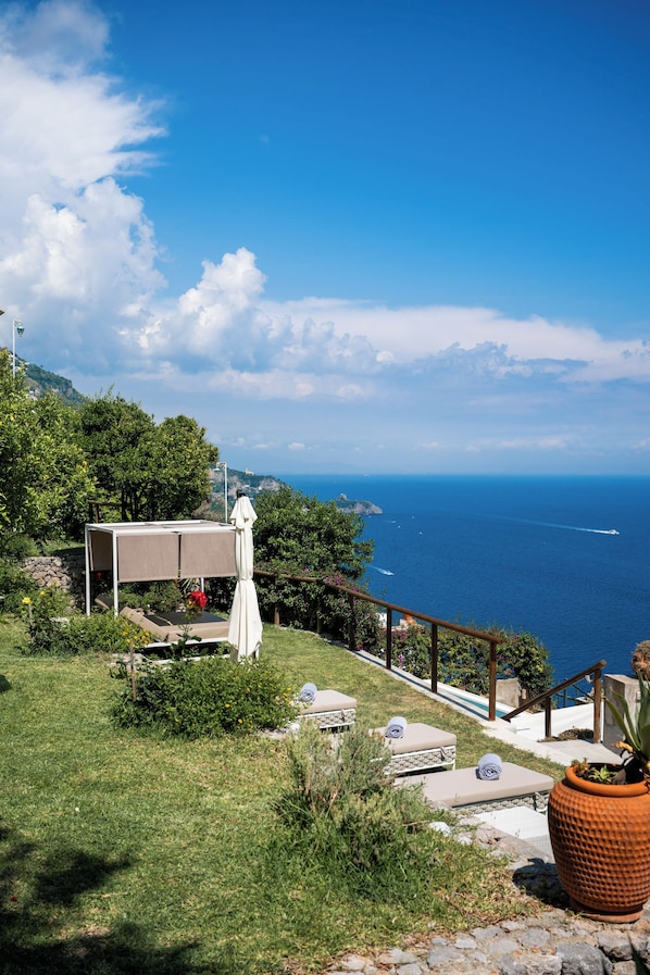 Une terrasse avec vue sur la mer, des sièges d’extérieur et une pergola.