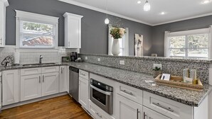 Eine moderne Küche mit weißen Schränken, Granit Arbeitsplatten und Edelstahlgeräten.