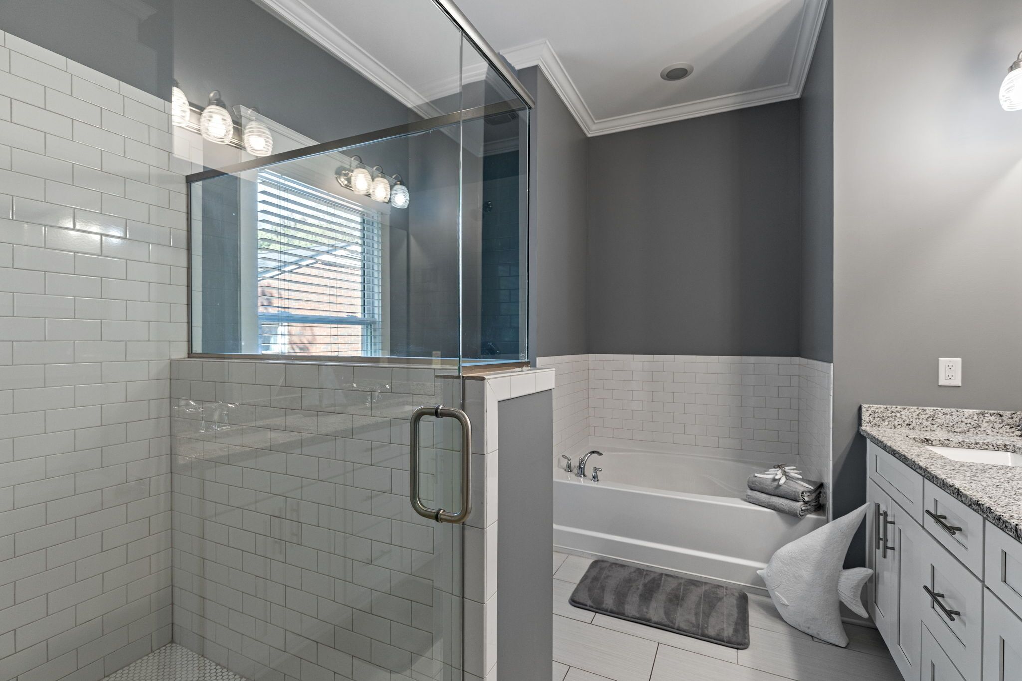 A modern bathroom with a glass-enclosed shower, a bathtub, and a vanity with a sink.