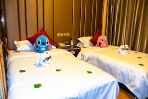 A hotel room with two beds, each with a plush toy and a pillow.