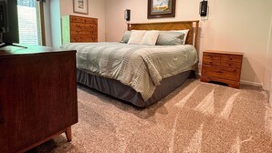Ein Schlafzimmer mit Bett, Schminktisch, Nachttischen und einem Fernseher.