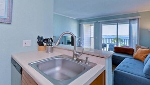 Una cocina con lavamanos, encimera y vistas a un balcón con mobiliario de exterior.
