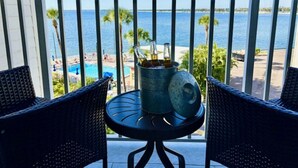 Un balcón con mesa y sillas, con vistas a una piscina y una playa.