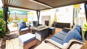Une terrasse extérieure avec des meubles en osier, une table et un espace abrité.