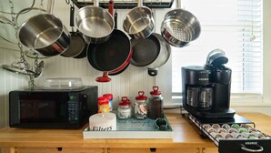 Une cuisine équipée d’un four à micro-ondes, d’une machine à café et de différents ustensiles de cuisine suspendus au-dessus du plan de travail.