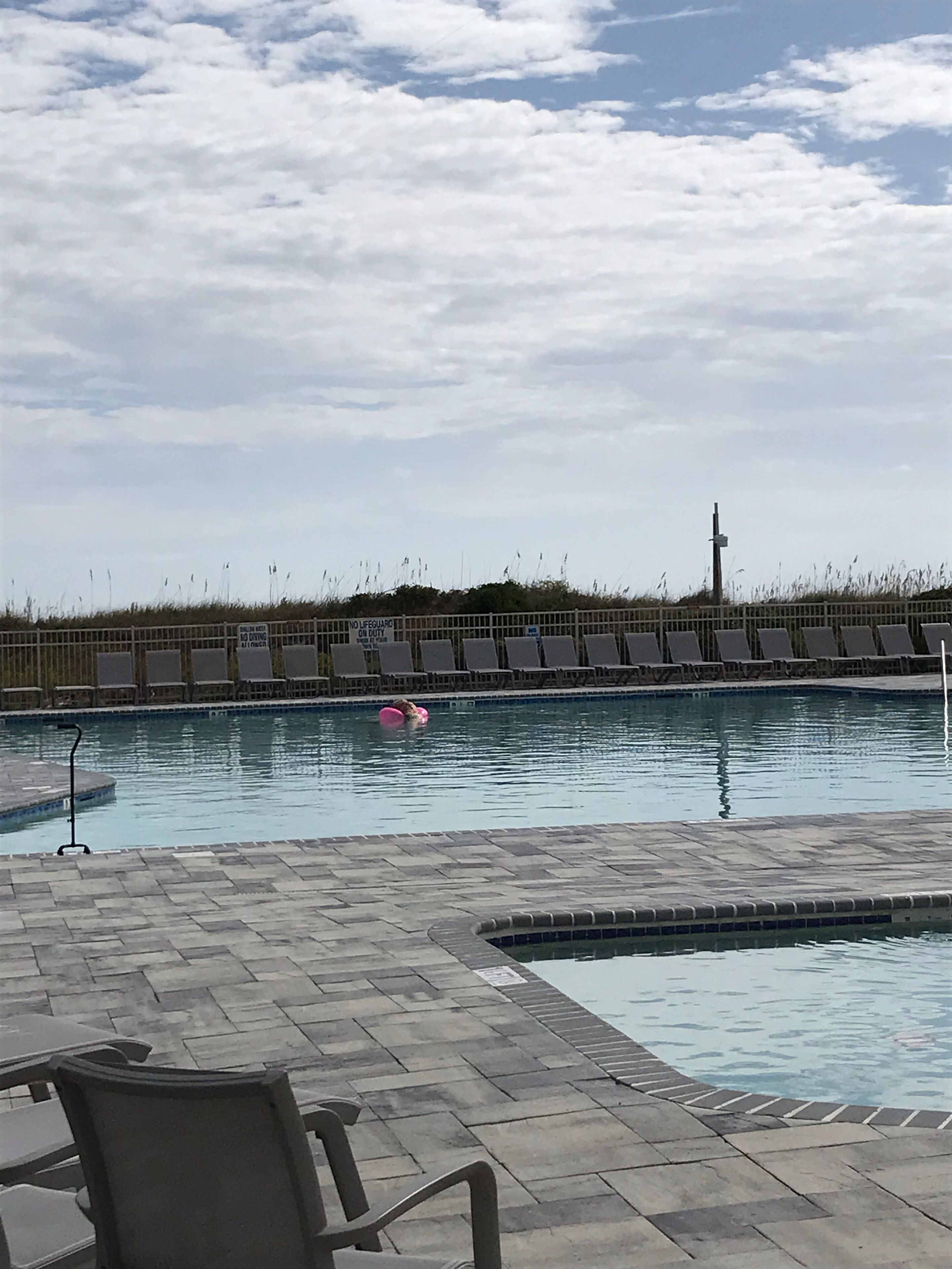 A swimming pool with lounge chairs and a lifeguard sign.