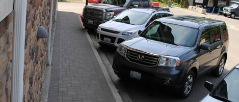 A parking lot with several cars parked along a brick sidewalk.