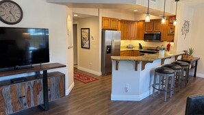 A modern kitchen with wooden cabinets, a stainless steel refrigerator, and a granite countertop.