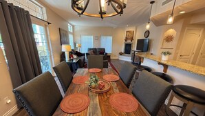 A dining area with a wooden table, grey upholstered chairs, and red woven placemats.
