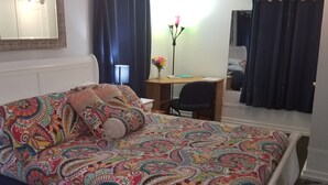 A bed with a colorful patterned bedspread, a bedside table with a lamp, and a desk with a chair. - Beach/Pier/Restaurants/Shopping/Outstanding Location...100yards to All! Parking  (Folly Beach)
