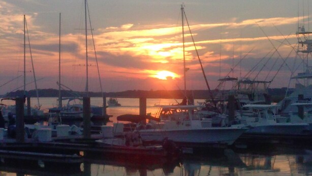 A marina with boats docked at the pier during sunset.