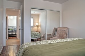 A bedroom with a bed, a chair, a mirror, and a door leading to a balcony. - Incredible 2BR Oceanside Condo w/Ocean Views (Oceanside)
