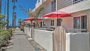 A hotel with a white exterior, red umbrellas, and a tiled walkway.