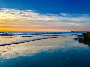 A beach with waves, a pier in the distance, and a clear sky. - Incredible 2BR Oceanside Condo w/Ocean Views (Oceanside)
