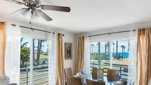 A dining area with a table, chairs, and a view of the beach.
