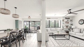 Un salon moderne avec un canapé blanc, une table basse et un coin repas comprenant des chaises et une table.