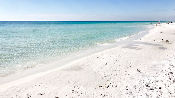 Une plage à l’eau turquoise et au sable blanc.