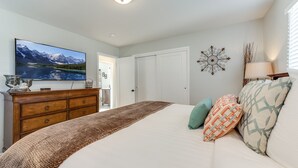 Un dormitorio con cama, cómoda, televisión y decoración mural.