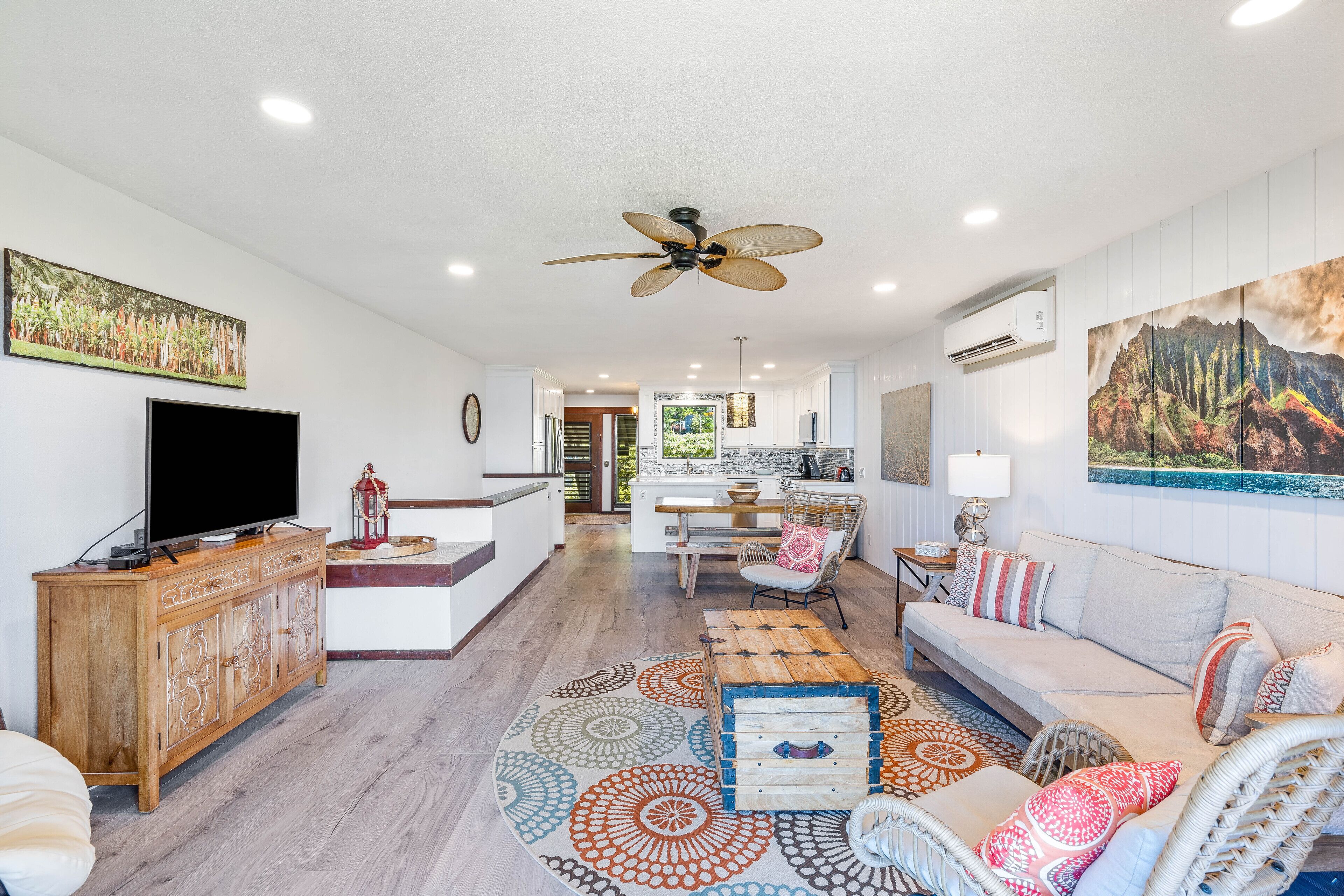 A spacious living area with a television, wooden cabinet, sofa, and patterned rug.