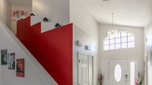 A staircase with a red accent wall, a white door, and a large window with a view of the outside. - Mickey's Lake Villa 2 only a few miles from Disney  (Kissimmee)