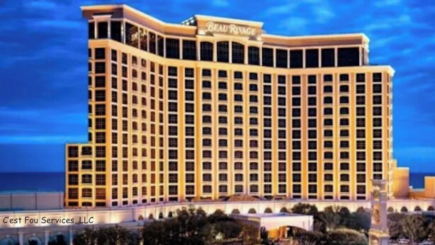 Un hotel grande de varios pisos con un diseño arquitectónico clásico, que presenta un llamativo cartel en la parte superior.