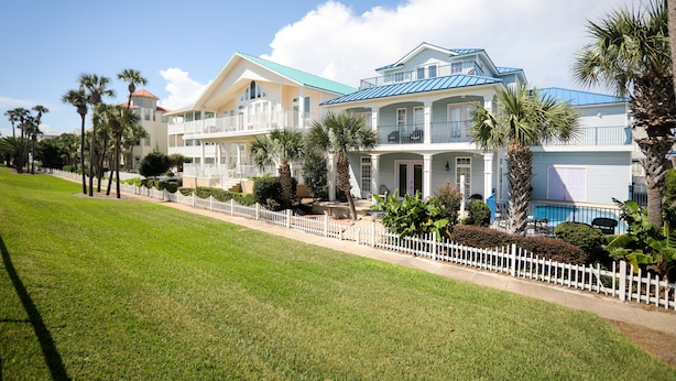 A two-story hotel with a white facade, multiple balconies, and a pool area. - WALK STEPS TO BEACH AND POOL.  GREAT LOCATION!  close to activities and shopping (Destin)