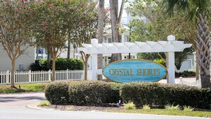 A sign for Crystal Shores with a white pergola structure. - WALK STEPS TO BEACH AND POOL.  GREAT LOCATION!  close to activities and shopping (Destin)