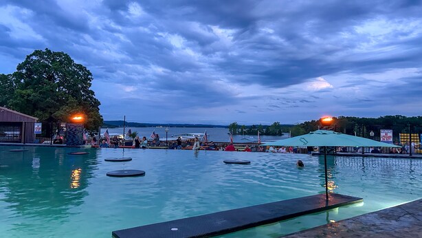 En swimmingpool med utsikt över vattnet och en molnig himmel.