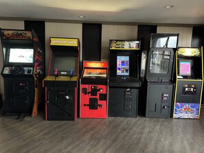 A row of arcade machines in a room with wooden flooring and a plain wall.