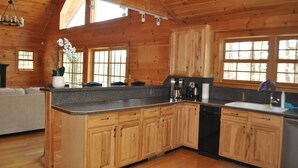 Ein Interieur einer Holzhütte mit Küchenbereich, der Holzausstattung, eine Granitarbeitsplatte und einen integrierten Geschirrspüler zeigt.