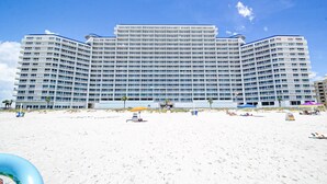 A large, multi-story hotel with a modern architectural design, featuring numerous balconies and a beachside location. - Lighthouse 910 - Perfect Spot in the Middle of the Building (Gulf Shores)