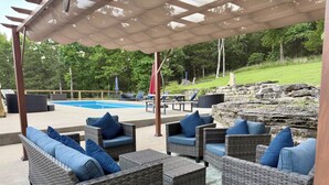 An outdoor patio area with wicker furniture and a pool.