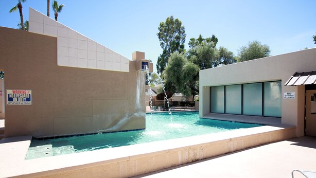 Una piscina con fuente, rodeada de edificios y árboles.