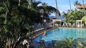 Un espace piscine avec des chaises longues, un coin salon abrité et une vue sur l’océan.