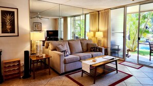 Un salon avec un canapé, une table basse, un téléviseur et des lampes.