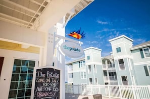 A beachfront hotel with a sign reading 'The Pointe' and a chalkboard sign advertising food and drinks.