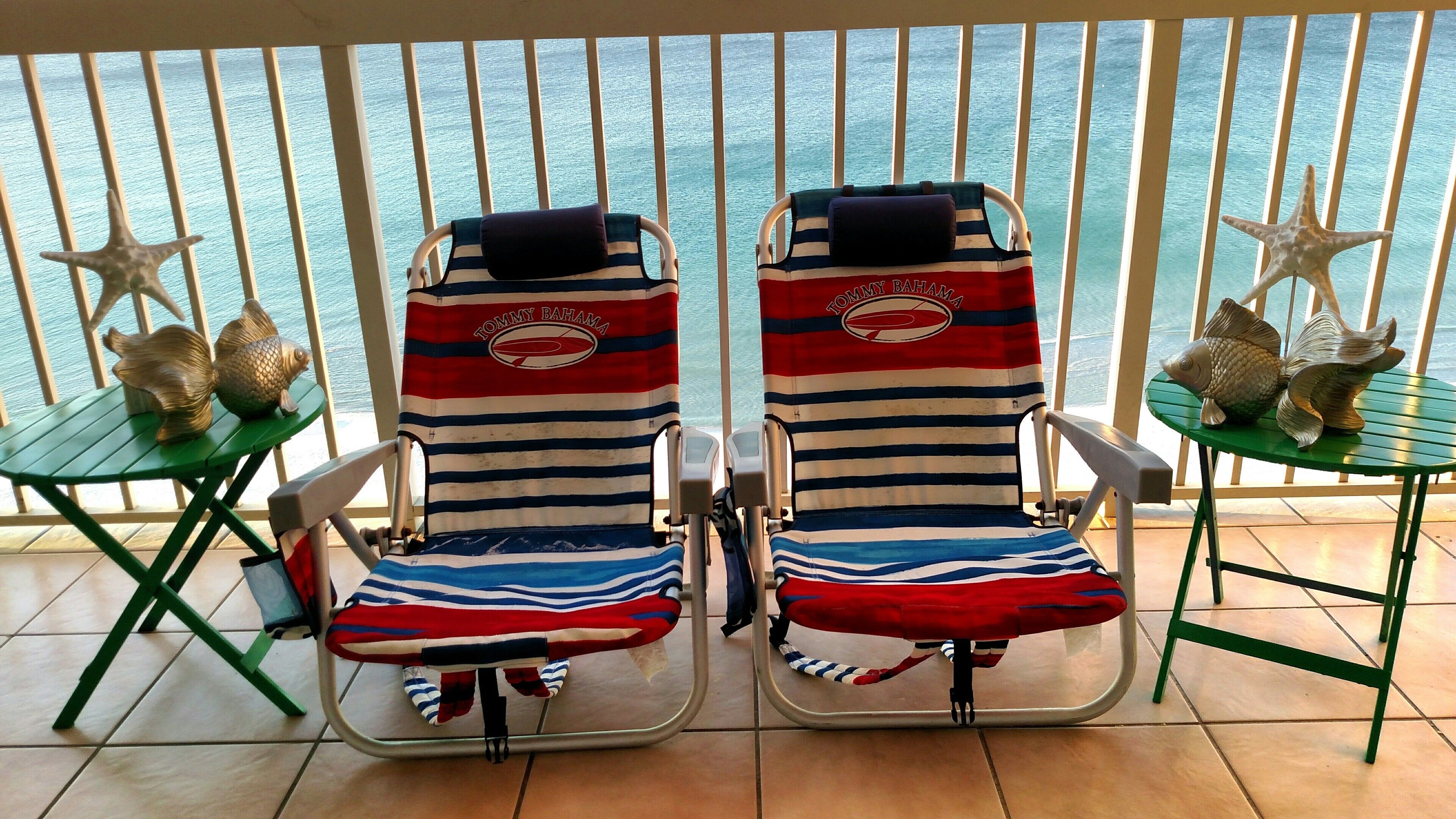 Deux chaises de plage avec des coussins à rayures et une décoration en forme d’étoile de mer, sur un balcon donnant sur la mer.